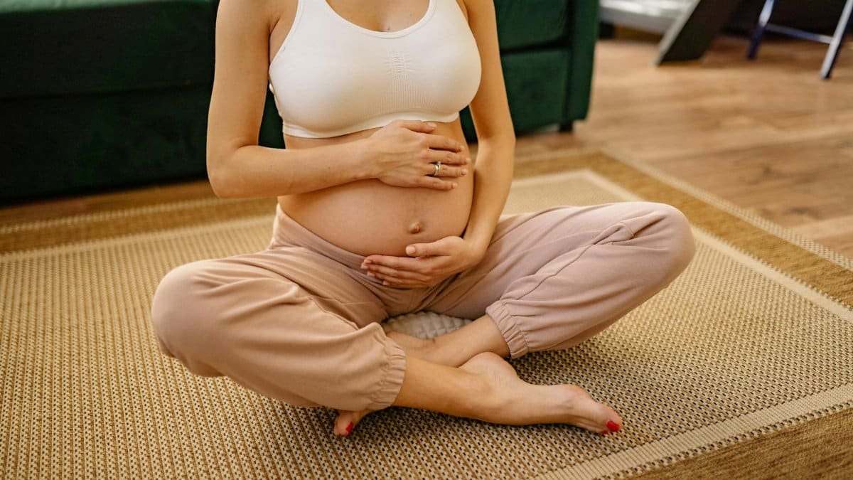 Expectant mother sitting in a serene setting practicing meditation and mindfulness indoors.