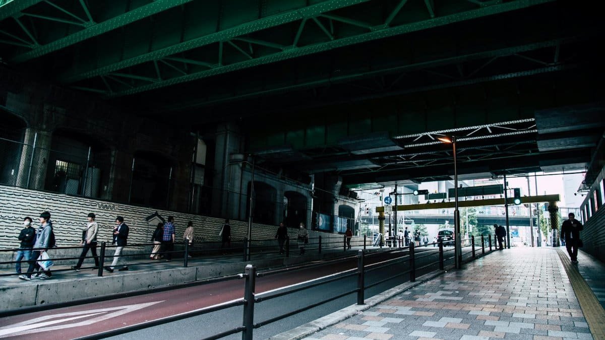 People walking under an urban overpass in Nagawa, Japan, showcasing daily commuting life.