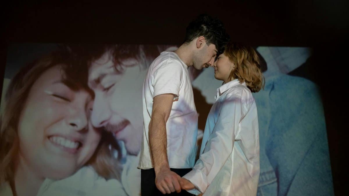 A couple embraces tenderly with a romantic image projected behind them, symbolizing love.