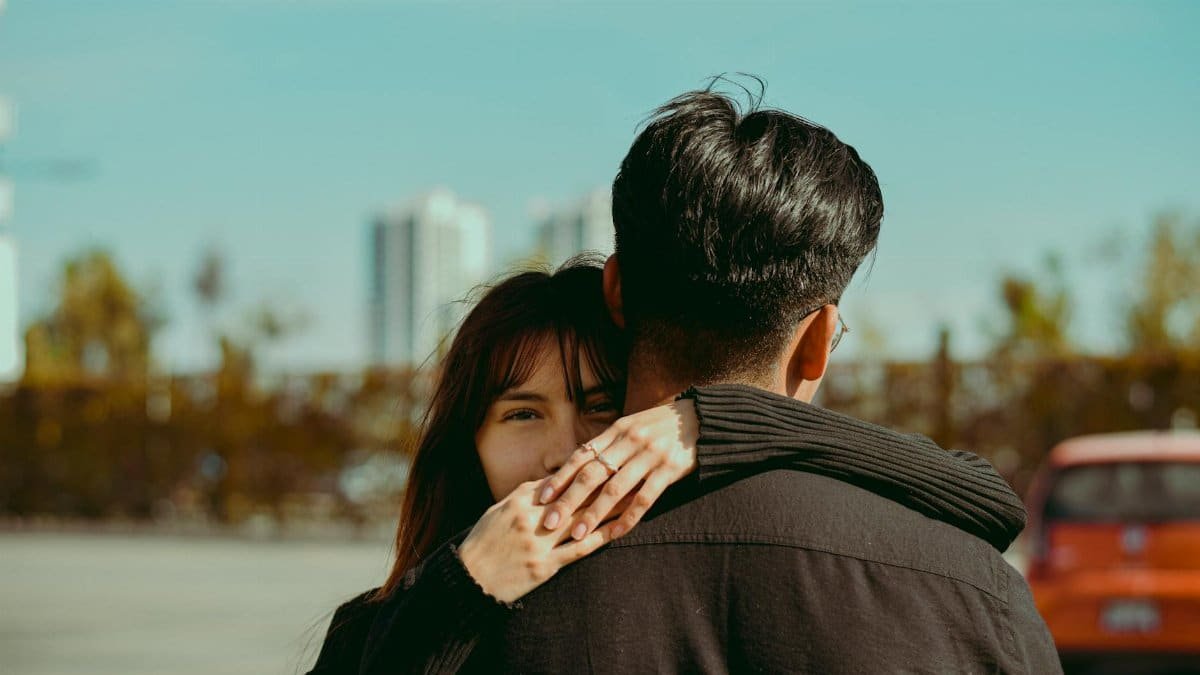 Young couple embracing with city skyline in the background. Emotional and romantic outdoor scene.