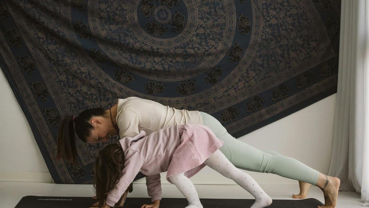 A mother and child practicing yoga together indoors, showcasing family bonding and wellness.