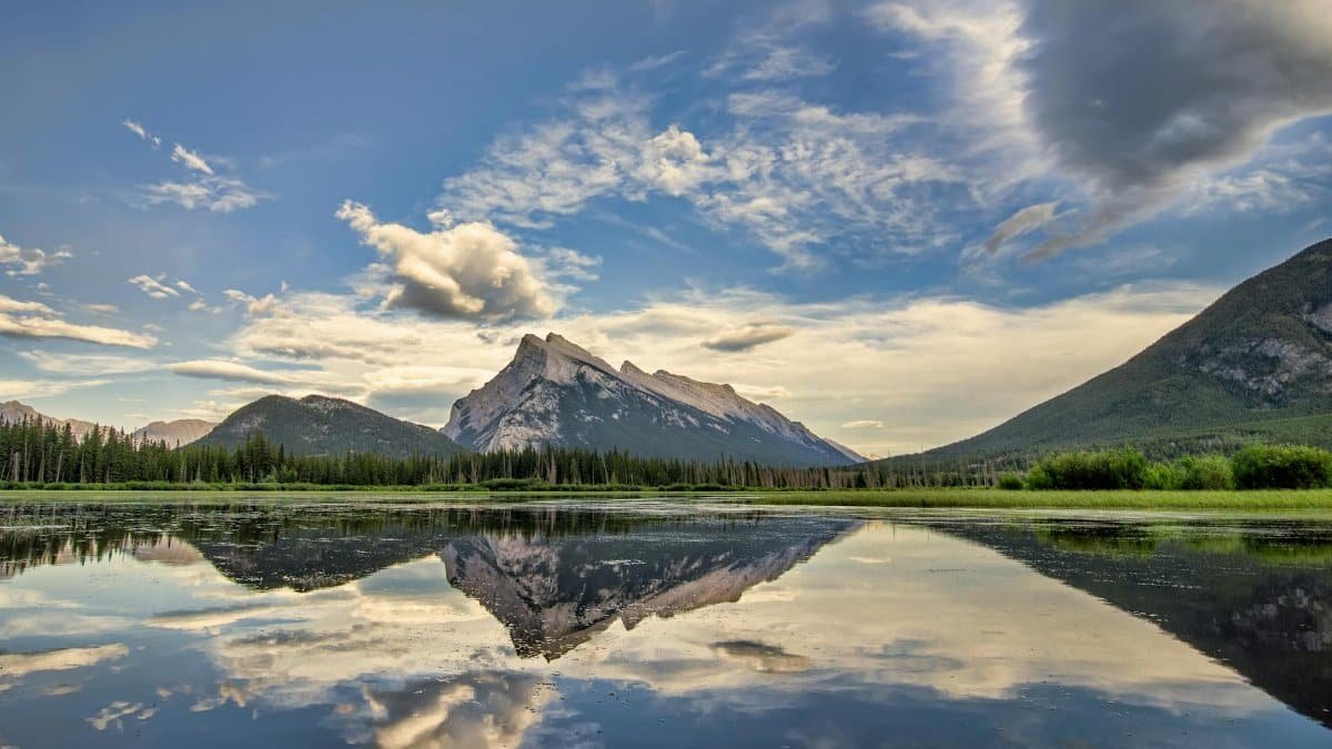 Serene landscape of Banff National Park with mountains and lake reflections at sunrise.