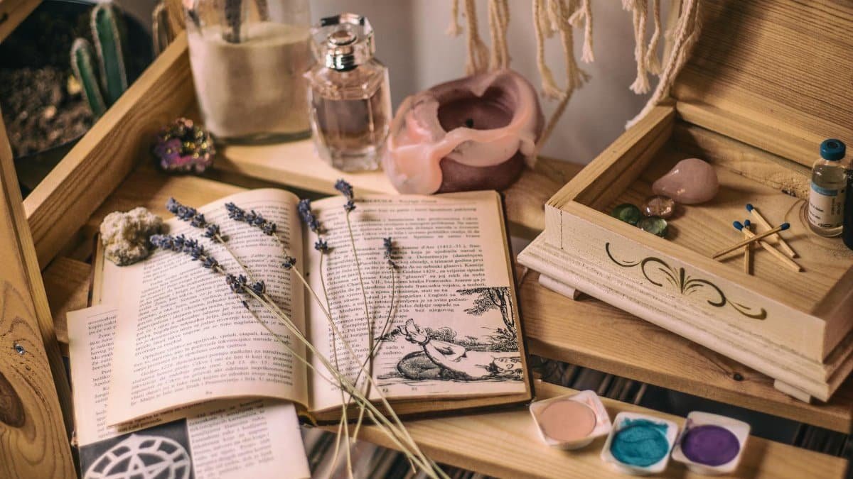 Aesthetic setup with books, lavender, crystals, and candles on a wooden shelf.