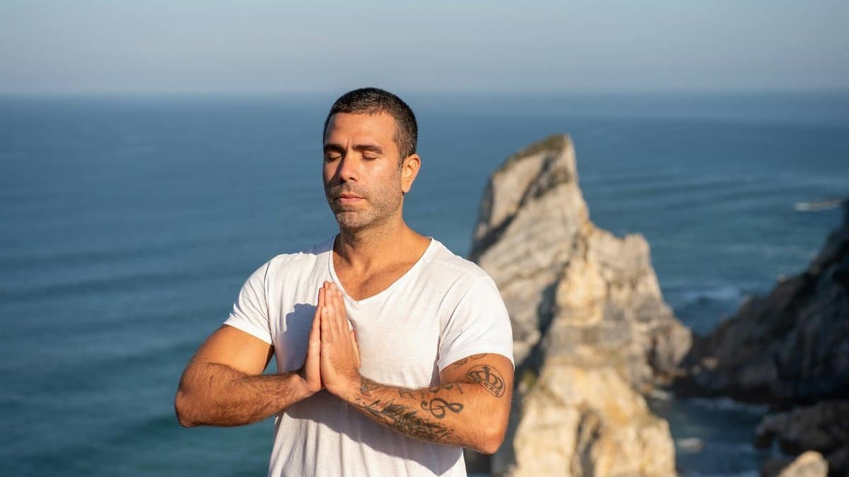 Man practicing meditation by the sea with a rocky backdrop in Portugal, capturing serenity and focus.