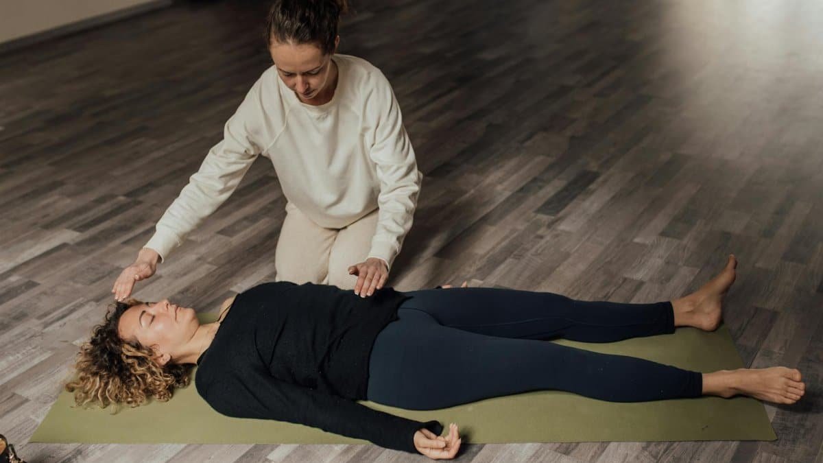 Two women involved in a serene meditation and healing practice session indoors.