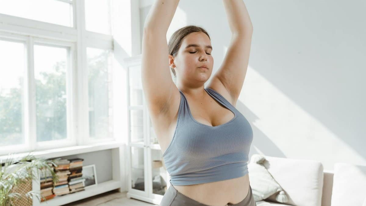 A plus size woman practicing body positivity and stretching at home for a healthy lifestyle.