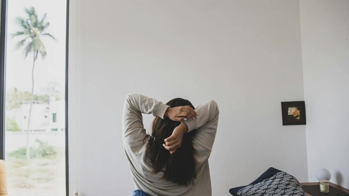 A woman stretching in a modern bedroom with morning light, offering a sense of relaxation and tranquility.