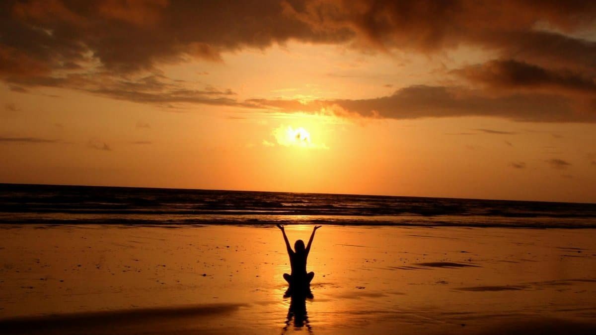 Peaceful meditation silhouette at sunset on a serene beach.