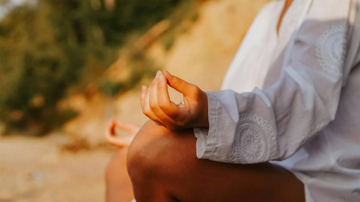 A close-up of a person meditating outdoors, capturing mindfulness at sunset on a beach.
