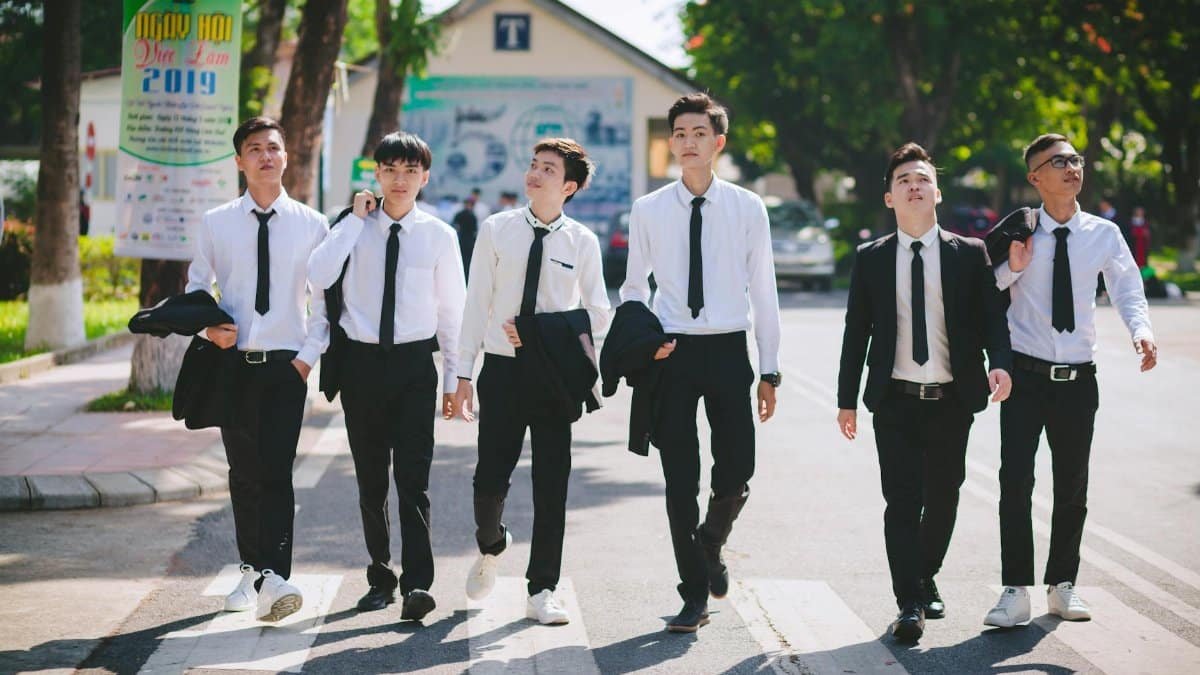 Group of young men in formal attire walking on a pedestrian lane in Hue, Vietnam.