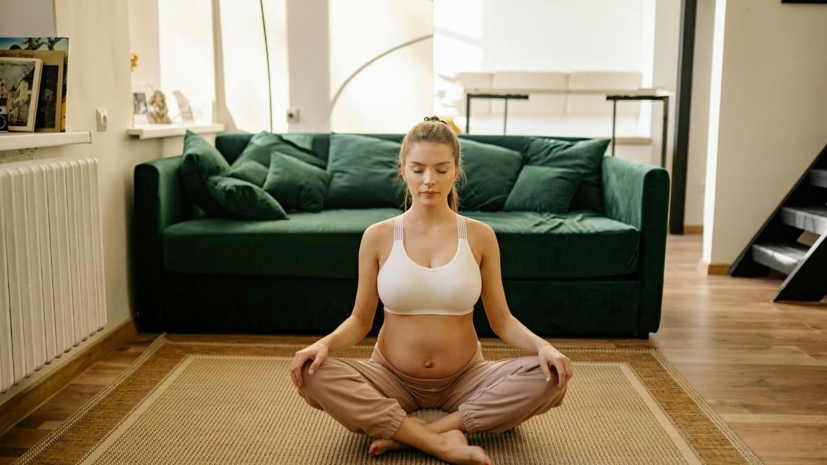 A serene pregnant woman practicing meditation indoors for healthy living.