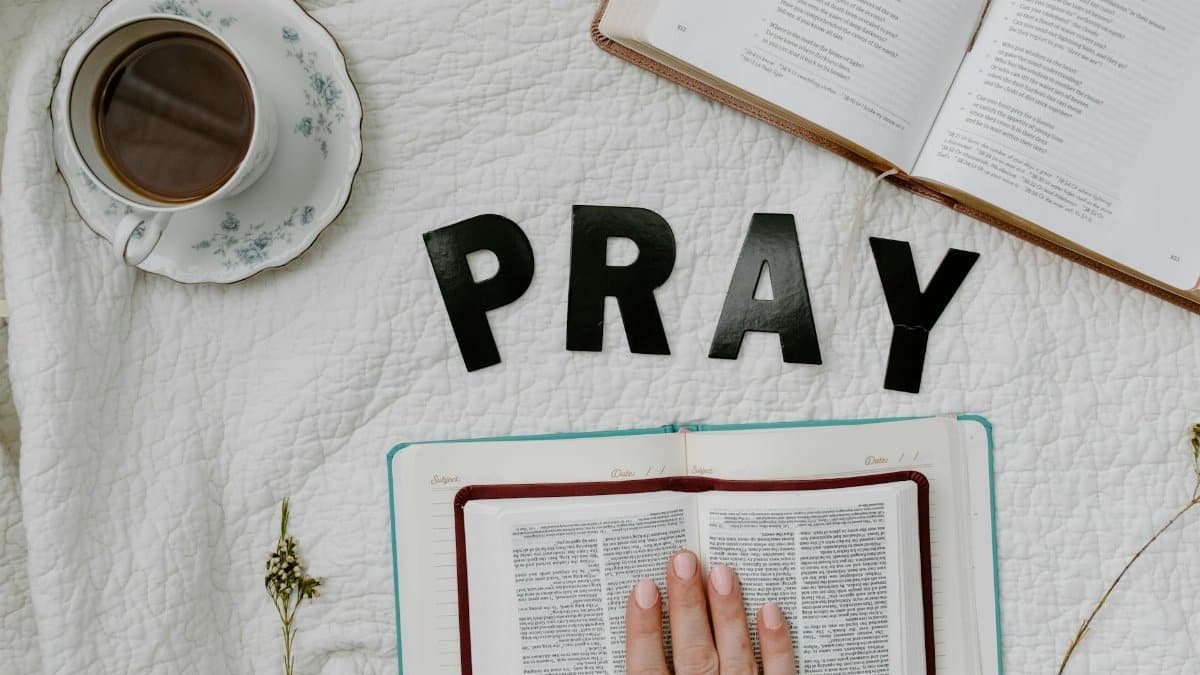 Flat lay of morning prayer routine including Bible, coffee, and 'PRAY' letters.