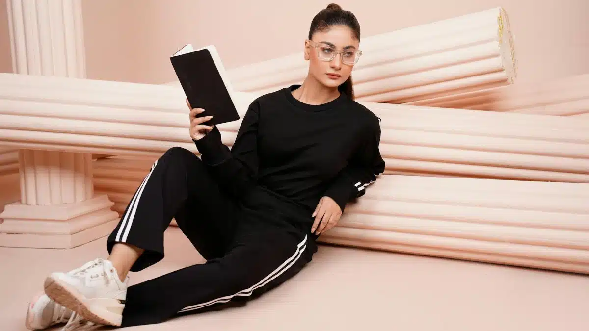 Woman in black athleisure holding a book against a classical column backdrop.