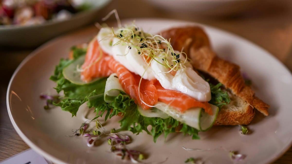 Mouthwatering croissant sandwich with fresh salmon, poached egg, and greens, perfect for brunch or lunch.
