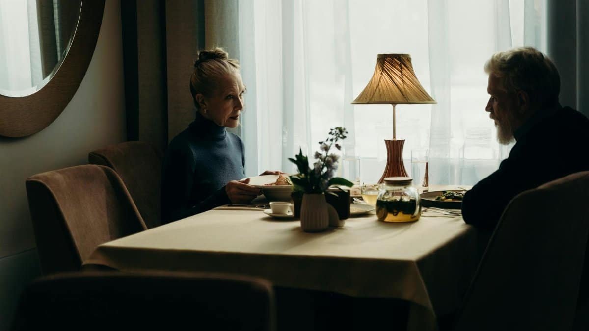 An elderly couple enjoys a meal in a warmly lit restaurant, capturing an intimate dining experience.