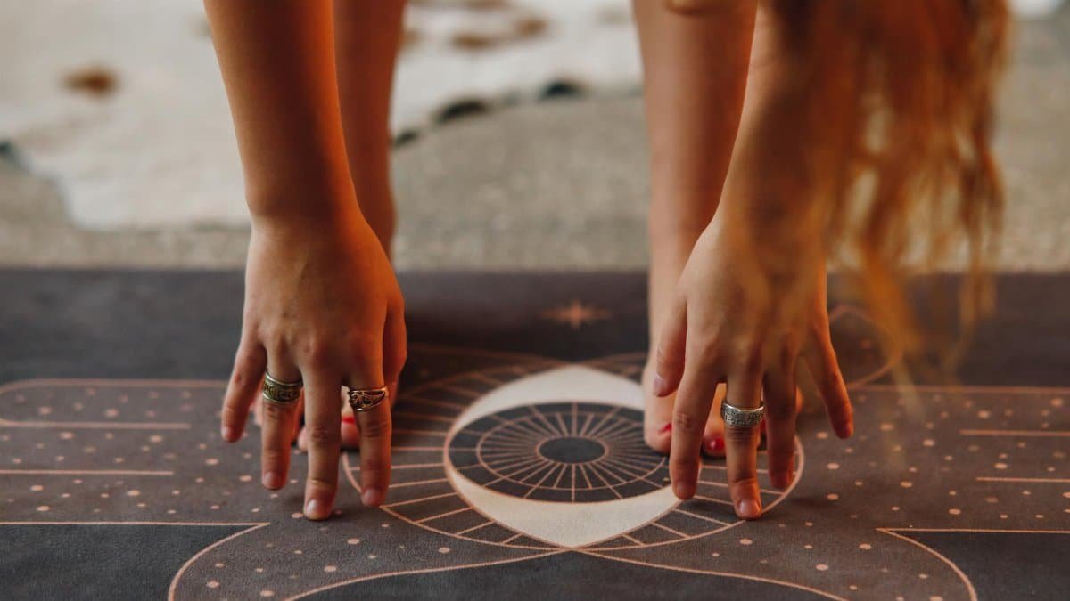 Detailed view of hands with rings in yoga pose on a decorative mat.