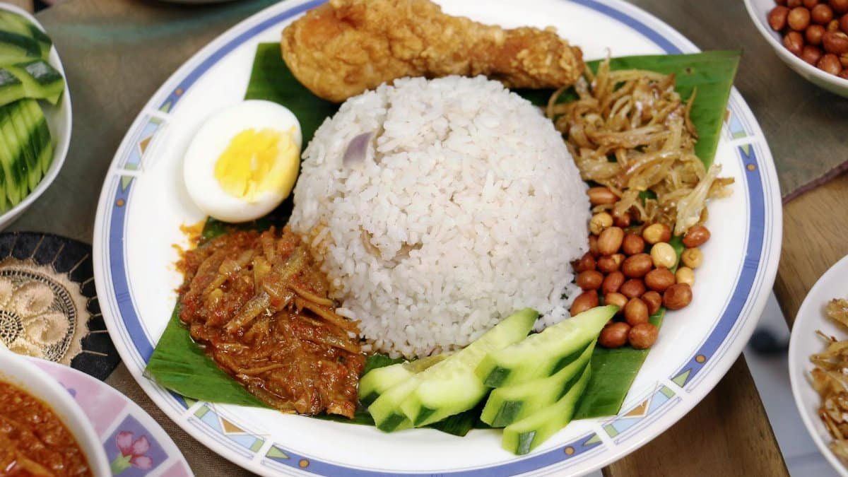 Delicious Nasi Lemak served with fried chicken, sambal, peanuts, and boiled egg.