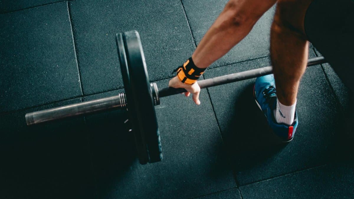 Close-up of a person lifting a barbell in an indoor gym, focusing on strength training.
