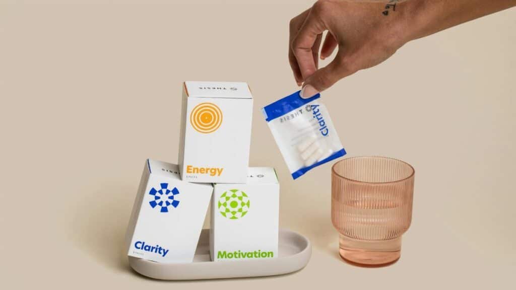 A close-up of dietary supplements for clarity, motivation, and energy with packaging and a hand reaching for a pouch.