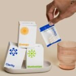 A close-up of dietary supplements for clarity, motivation, and energy with packaging and a hand reaching for a pouch.