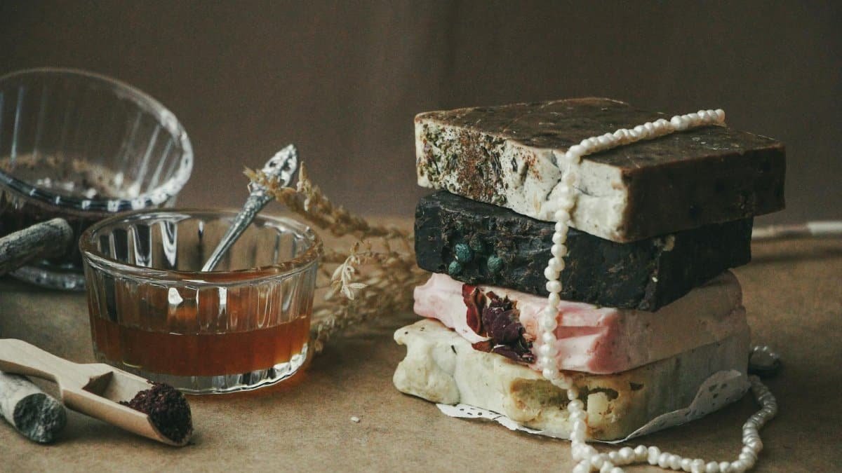 A stack of rustic handmade soap bars with natural ingredients and honey in a cozy setting.