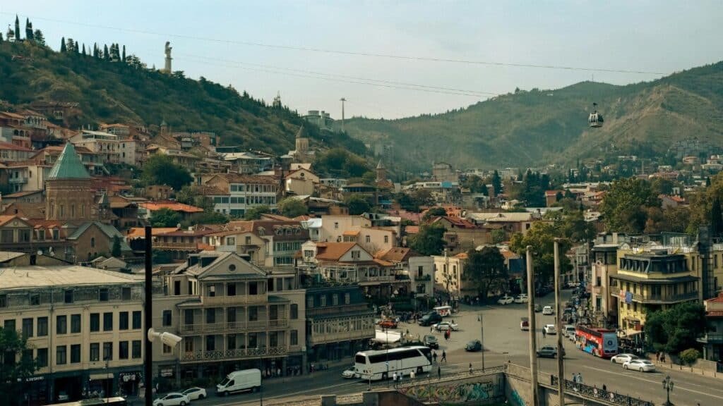 A scenic view of Tbilisi, Georgia, showcasing historic architecture and cable car over the city.