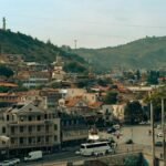 A scenic view of Tbilisi, Georgia, showcasing historic architecture and cable car over the city.