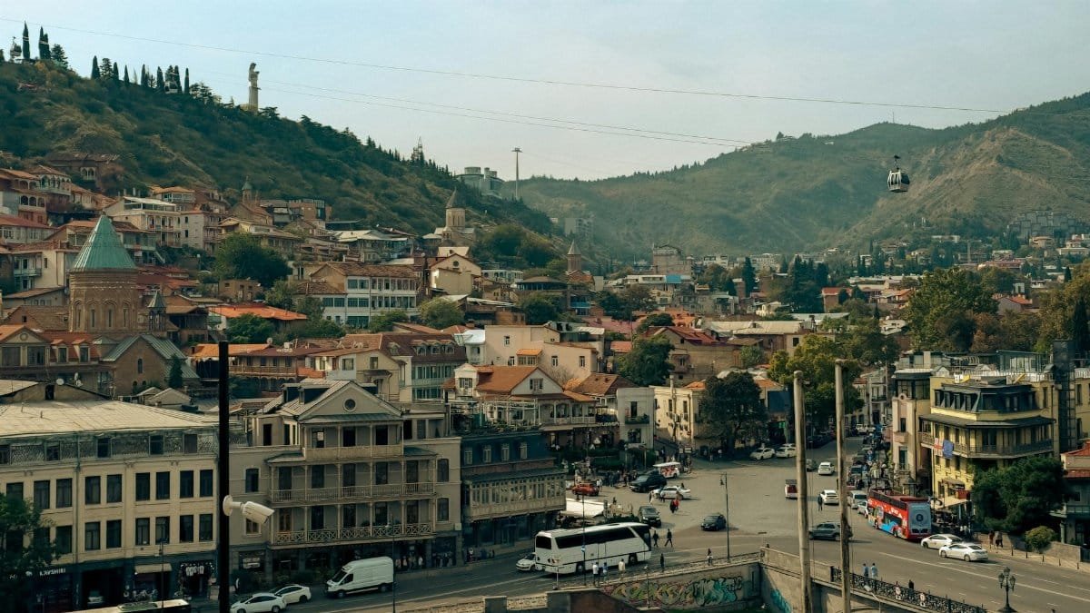 A scenic view of Tbilisi, Georgia, showcasing historic architecture and cable car over the city.