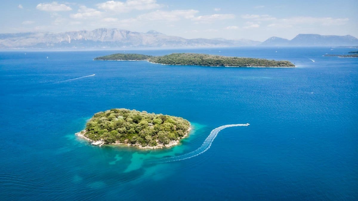 Amazing aerial view of boats floating in turquoise sea near islands with lush green vegetation on sunny day