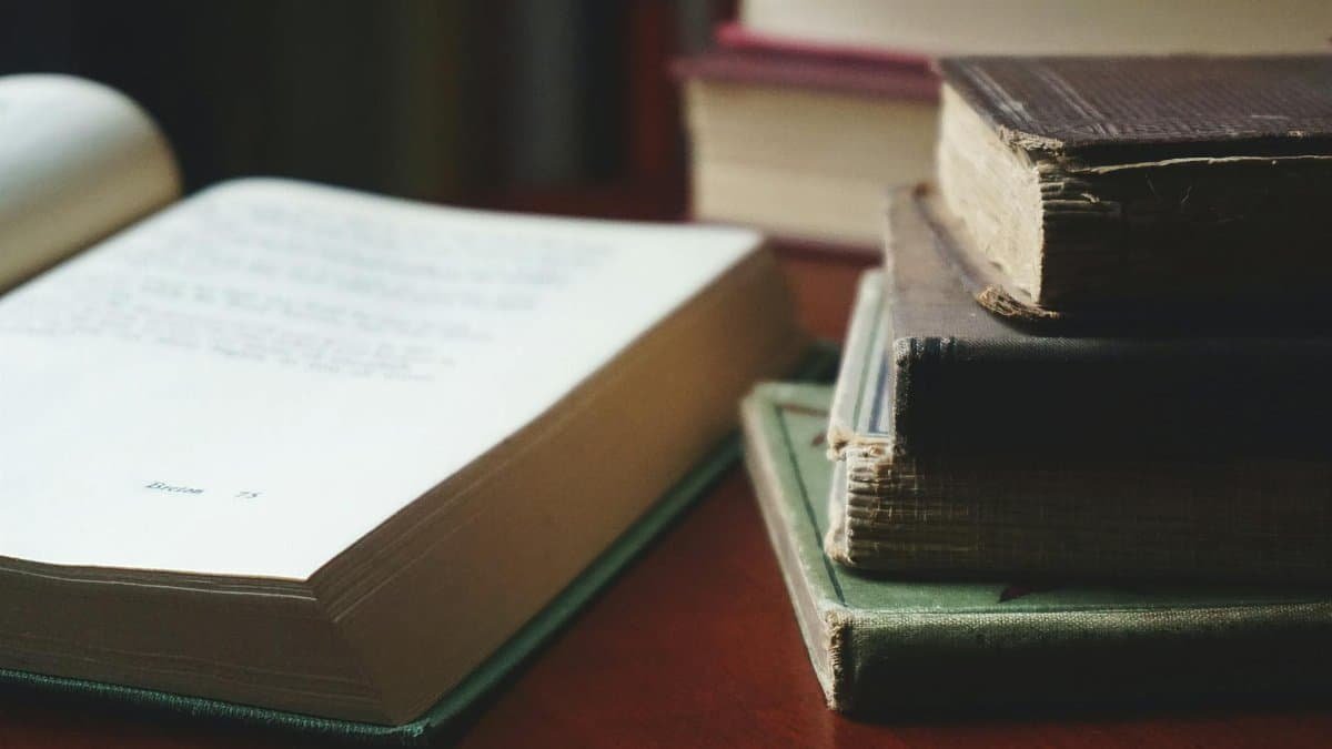 A collection of aged books stacked neatly on a wooden table for reading enthusiasts.