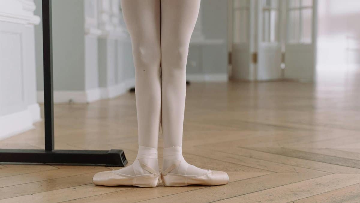 Close-up of a ballerina's feet in pointe shoes during practice in a dance studio.