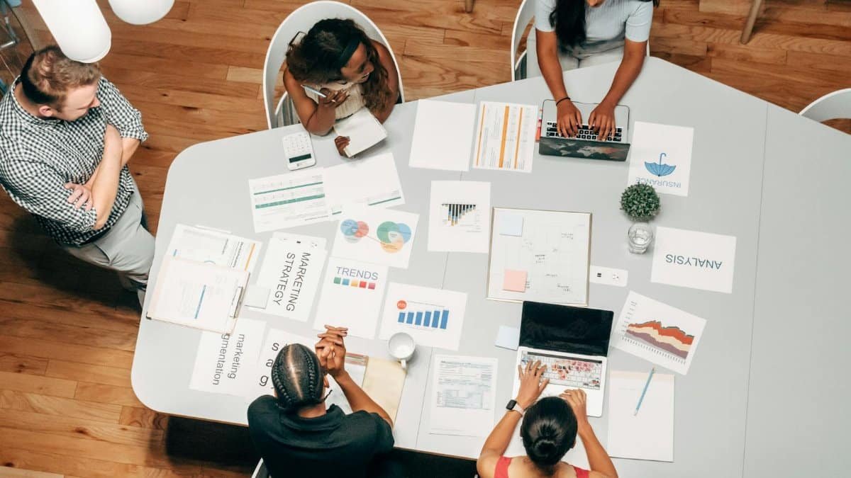 A diverse group working on marketing strategies with charts and laptops in an office setting.