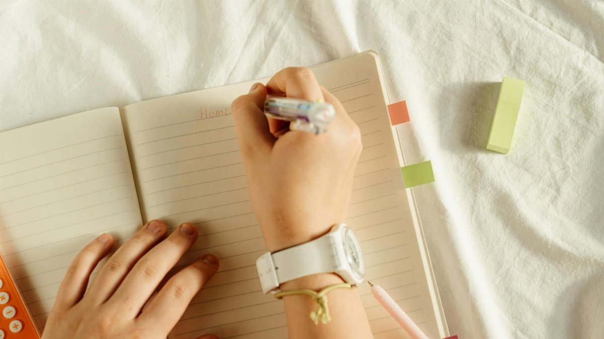 A close-up view of hands writing notes in a notebook with a pen, ideal for study concepts.