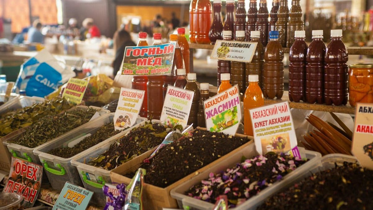 Explore a vibrant display of teas and honey at a bustling market stall in Sochumi.