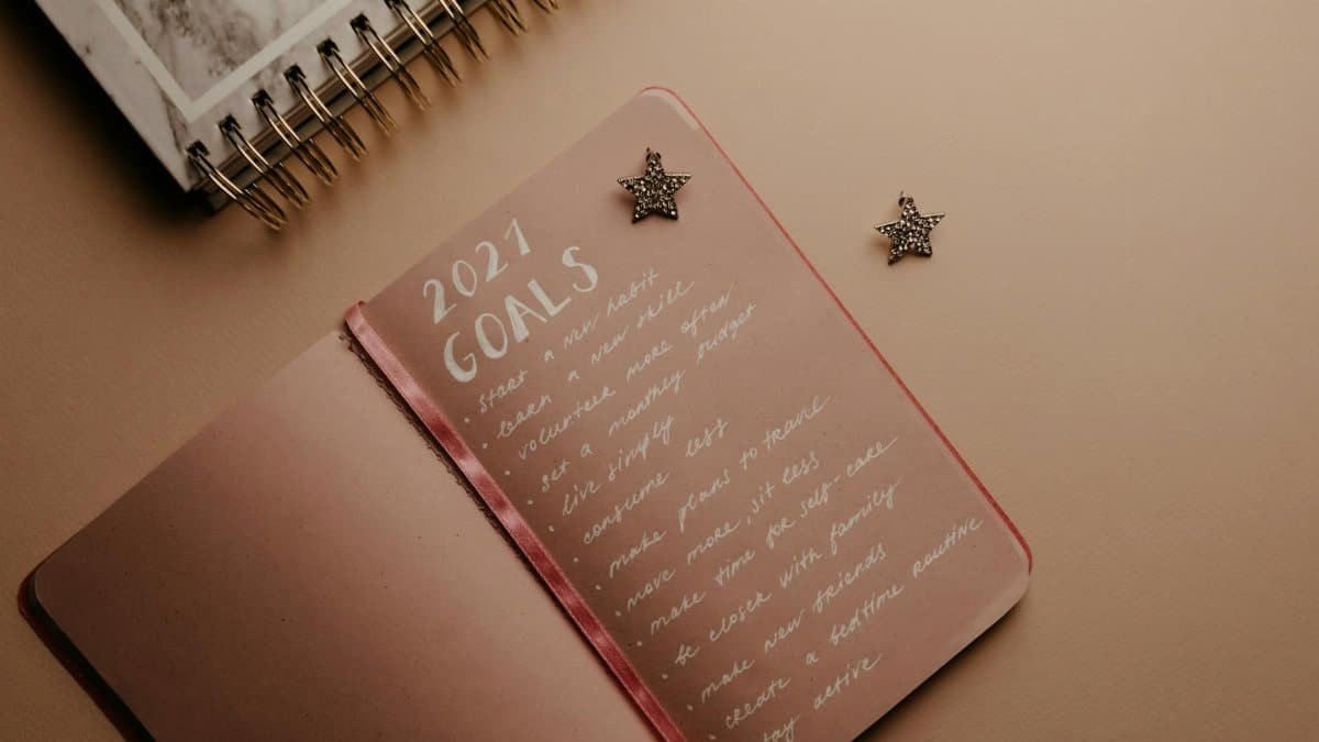 Top view of a 2021 goals notebook with handwritten list and star decorations, ideal for planning inspiration.