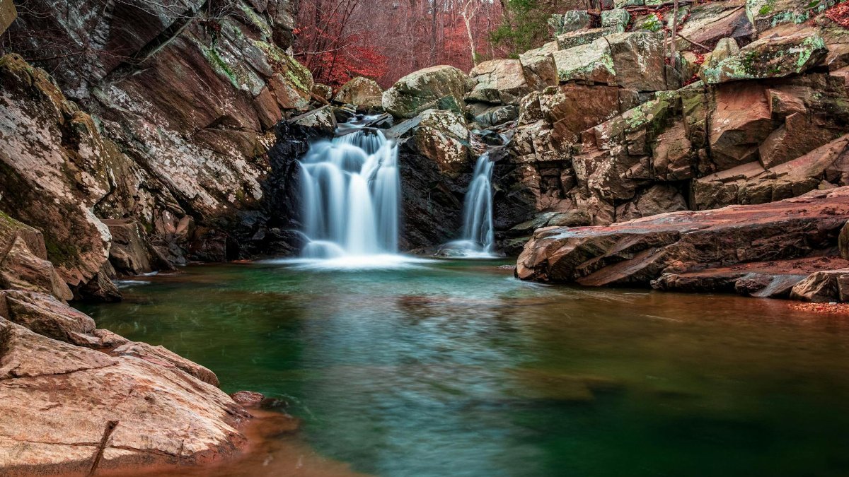 Tranquil waterfall surrounded by rocky cliffs and vibrant foliage in Virginia. A perfect nature escape.