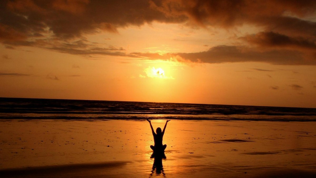 Peaceful meditation silhouette at sunset on a serene beach.