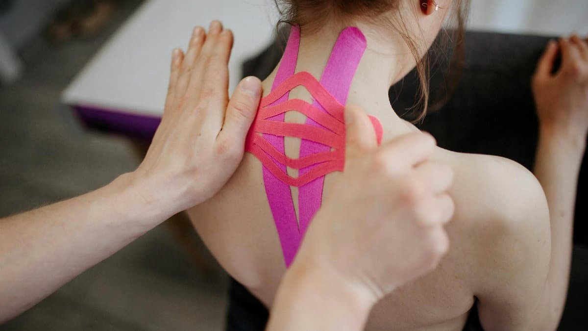 A close-up image of kinesio tape being applied to a person's back, showcasing healthcare and treatment.
