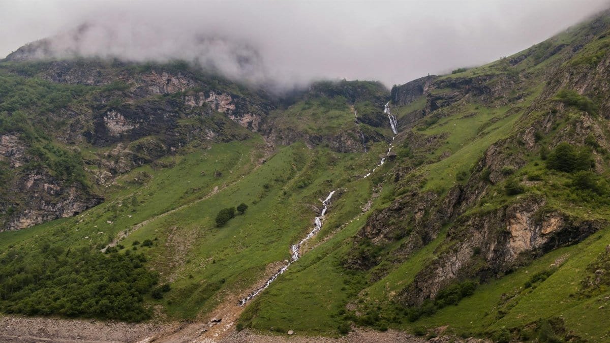 Explore the tranquility of a lush, fog-covered mountain landscape with cascading waterfalls.