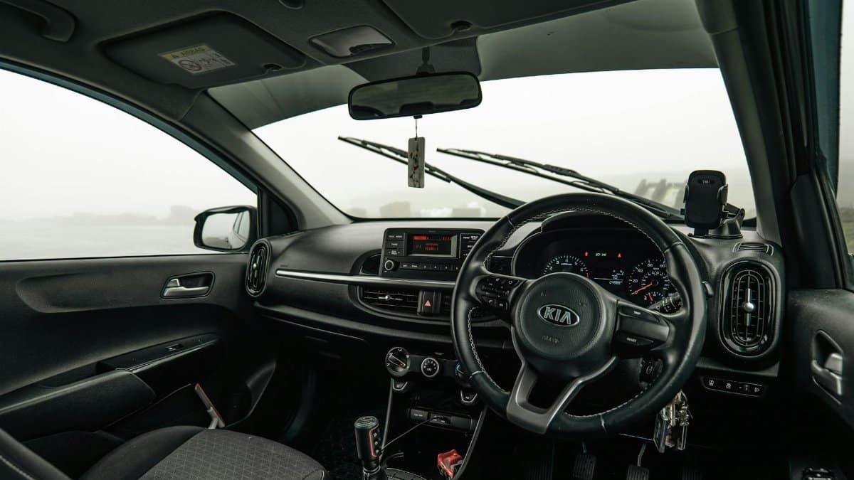 View of a Kia car interior with foggy landscape outside, showing the dashboard and steering wheel.