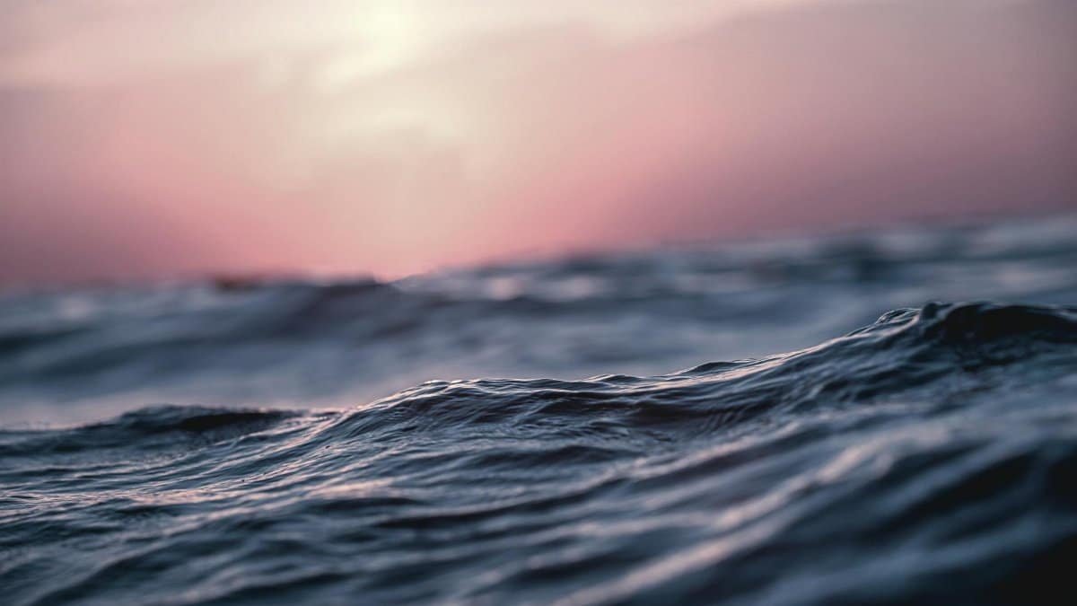 Close-up of gentle ocean waves during a calming sunset, capturing tranquility.