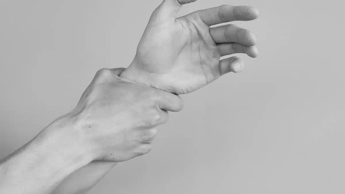 Grayscale image of hands gripping a wrist, symbolizing tension or support.