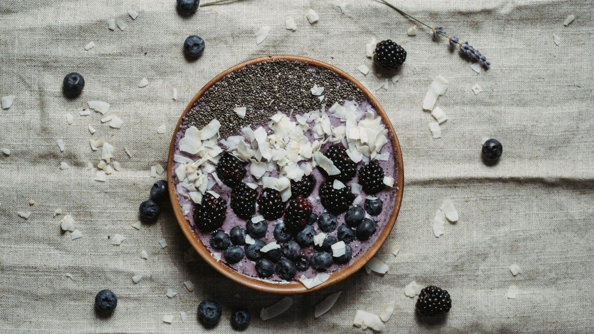 A nutritious berry smoothie bowl topped with chia seeds, blackberries, blueberries, and coconut flakes.