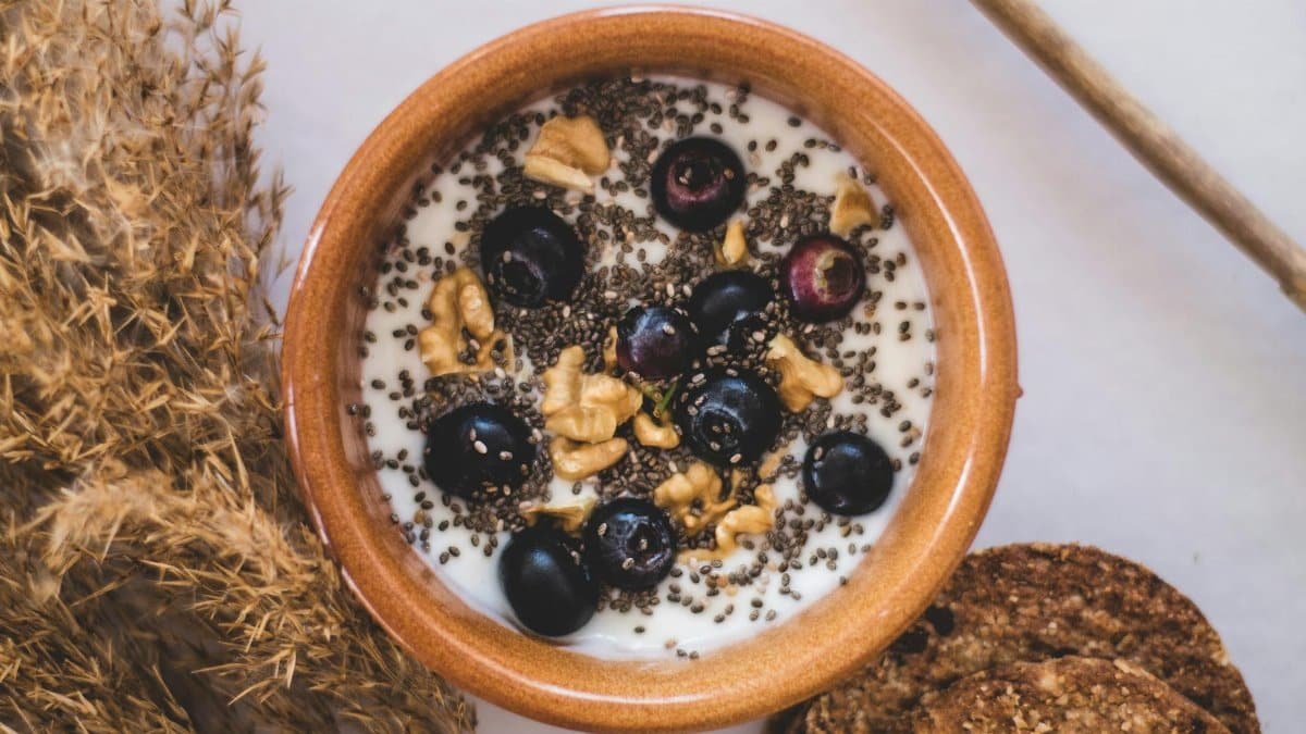 Top view of a nutritious bowl with yoghurt, blueberries, chia seeds, and walnuts.