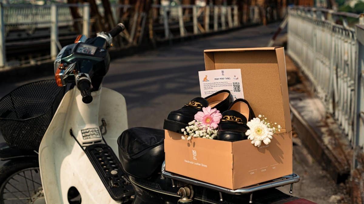 A pair of leather shoes with flowers in a box on a motorbike on Long Bien Bridge.