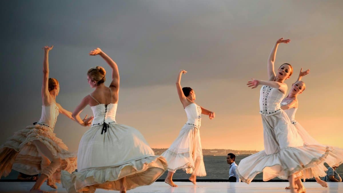 Elegant ballerinas performing a captivating dance at sunset outdoors.