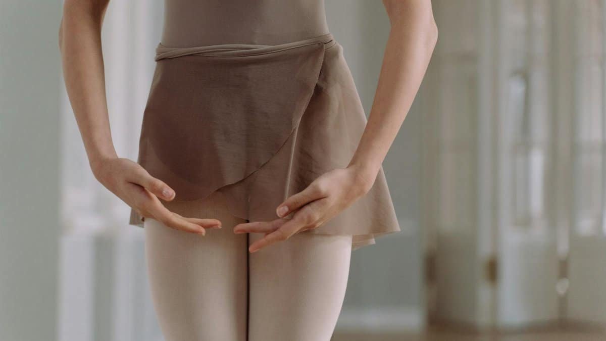 A close-up of a ballerina's graceful hands and posture, capturing elegance in a dance studio setting.