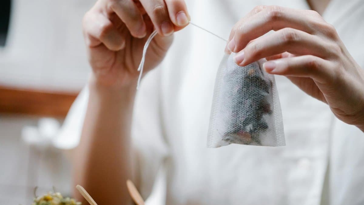 Close-up of hands holding and preparing an herbal tea bag. Perfect for wellness and lifestyle themes.