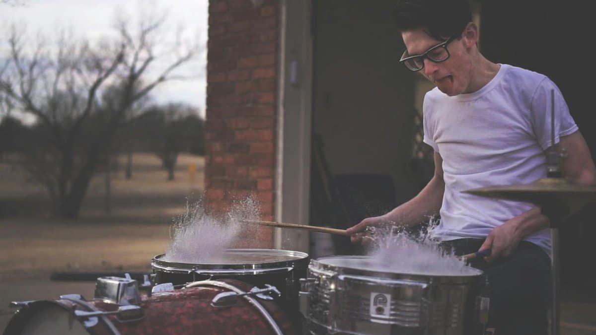 Energetic drummer playing outdoors with a splash effect. Captured in dynamic motion.