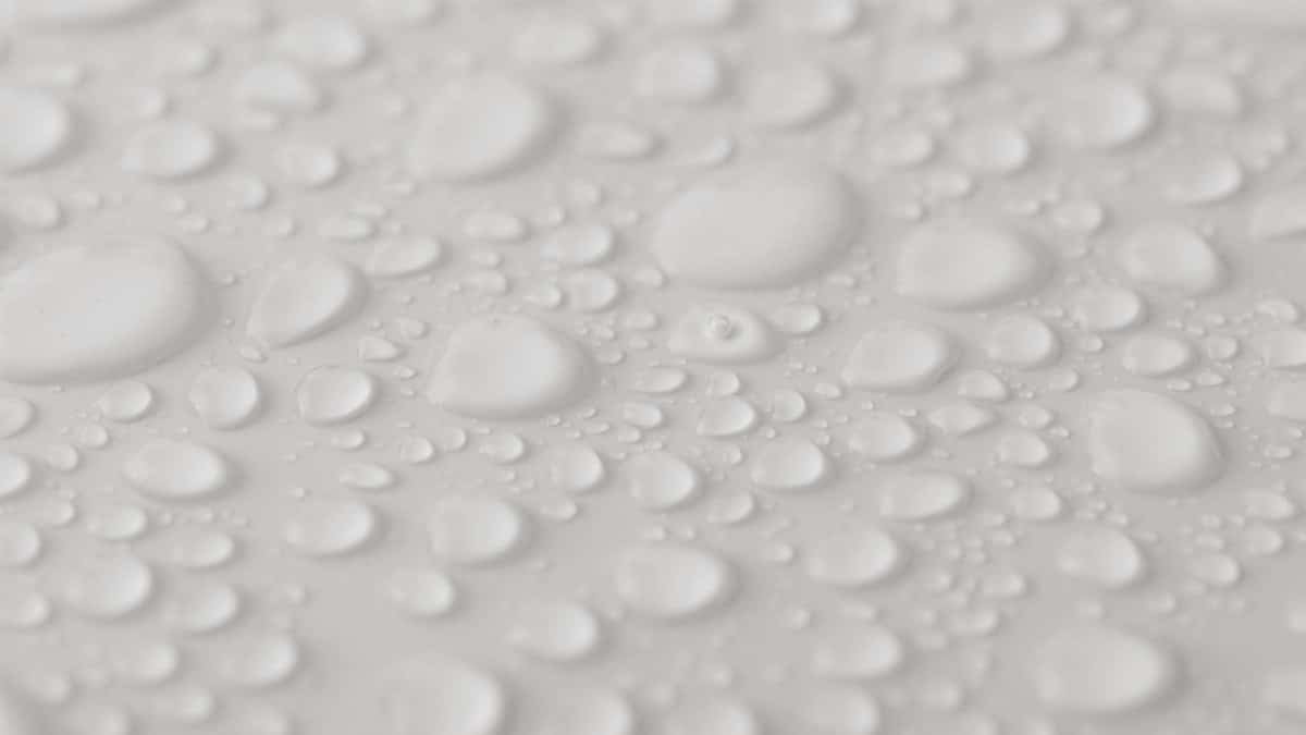 Detailed close-up of water droplets on a smooth, white surface, showcasing texture and clarity.